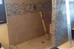 Frameless floor to ceiling shower doors in process of being installed.